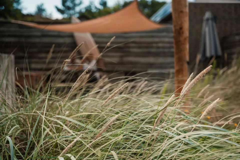 Doorkijk over het terras met schaduwdoek vanuit het hoge duingras