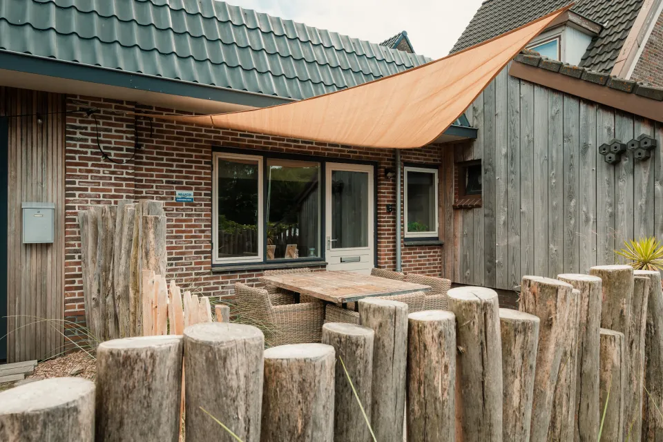 Houten krukken rond een tafel op het terras voor de gevel van de accommodatie