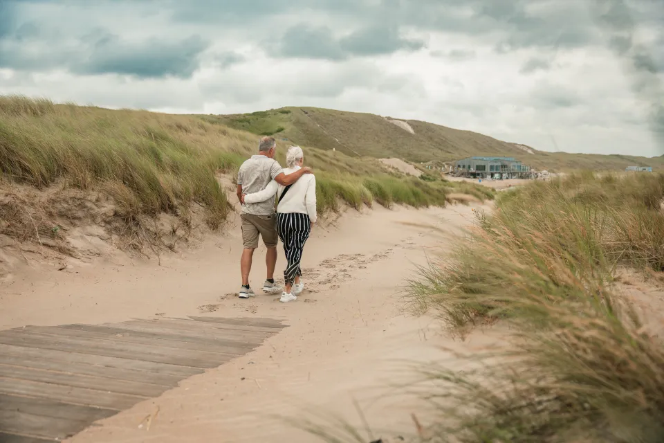Wandelaars op de duinovergang met het strandpaviljoen in de verte