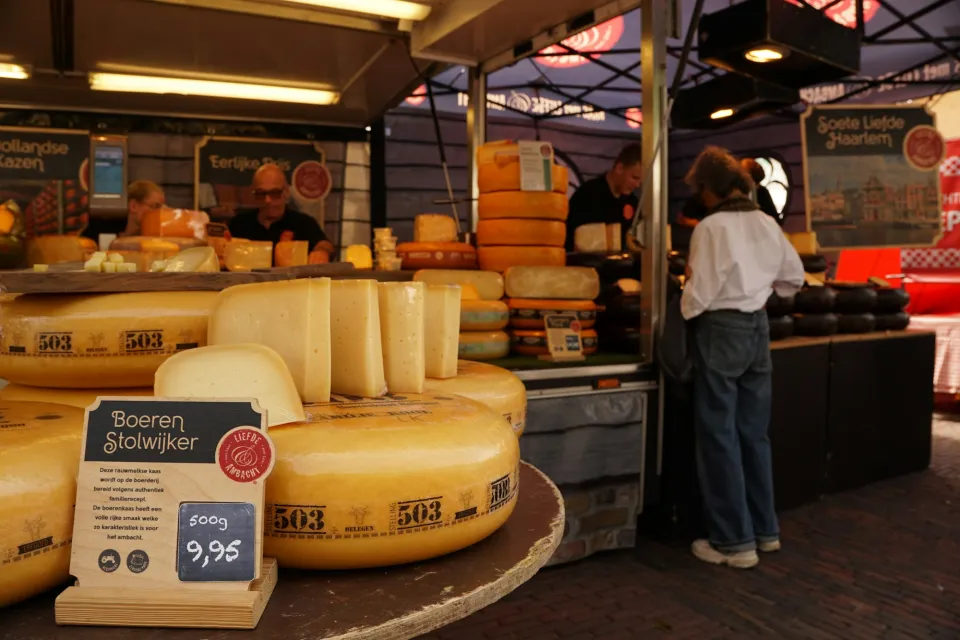Gele kaaswielen op een marktkraam met bezoekers
