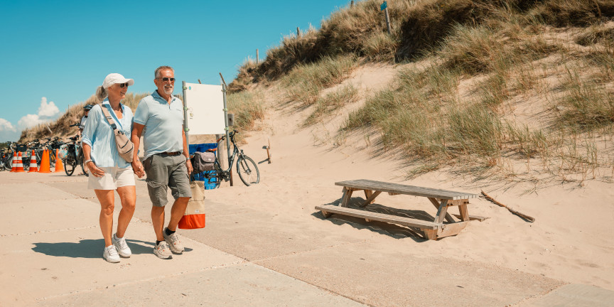 Walkers with beach bags on the dune crossing to the beach